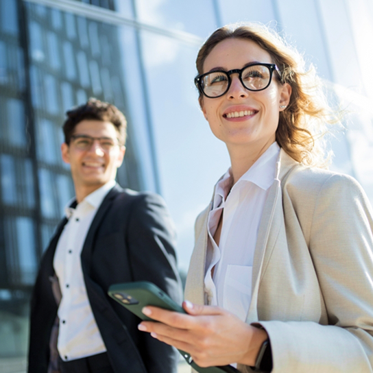 A business couple in front of a mirrored building