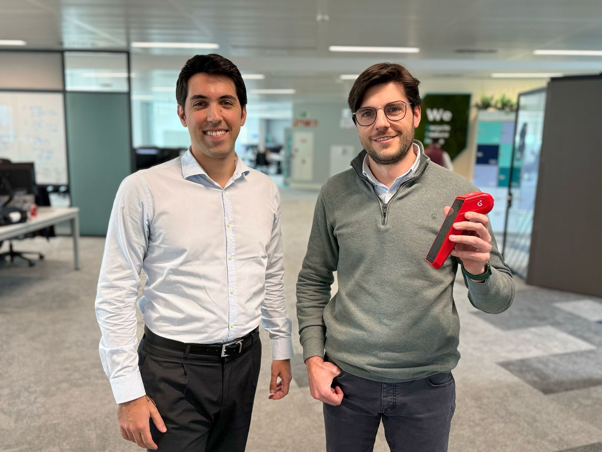 Two men in the Getnet office, one of them with a TPA in his hand.
