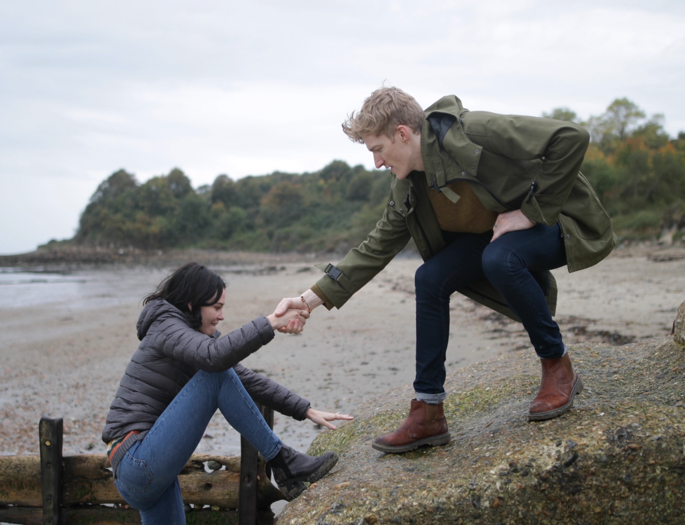 A man helping a woman climb a high rock