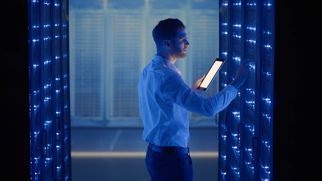 A man with a tablet in a server room