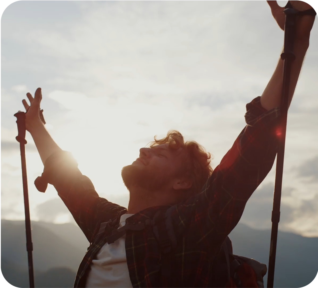 A man with open arms against a landscape backdrop.